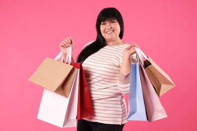 Photo of Beautiful overweight mature woman with shopping bags on pink background