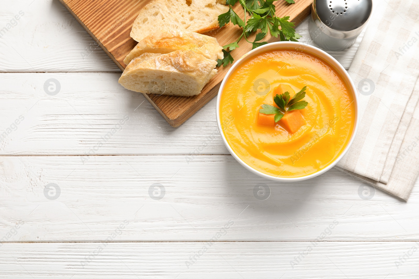 Photo of Flat lay composition with pumpkin cream soup in bowl on wooden background. Space for text