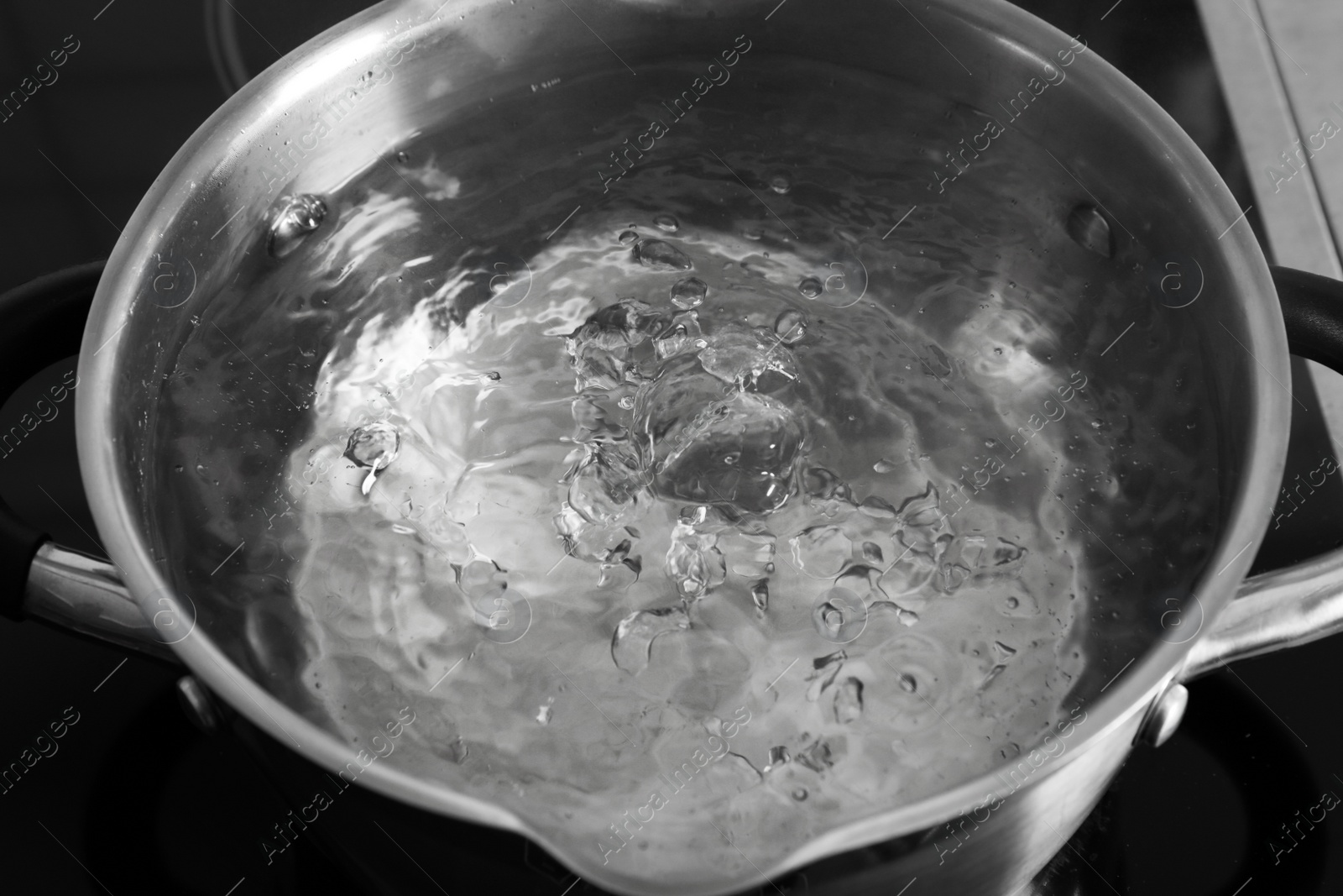 Photo of Pot with boiling water on stove, closeup