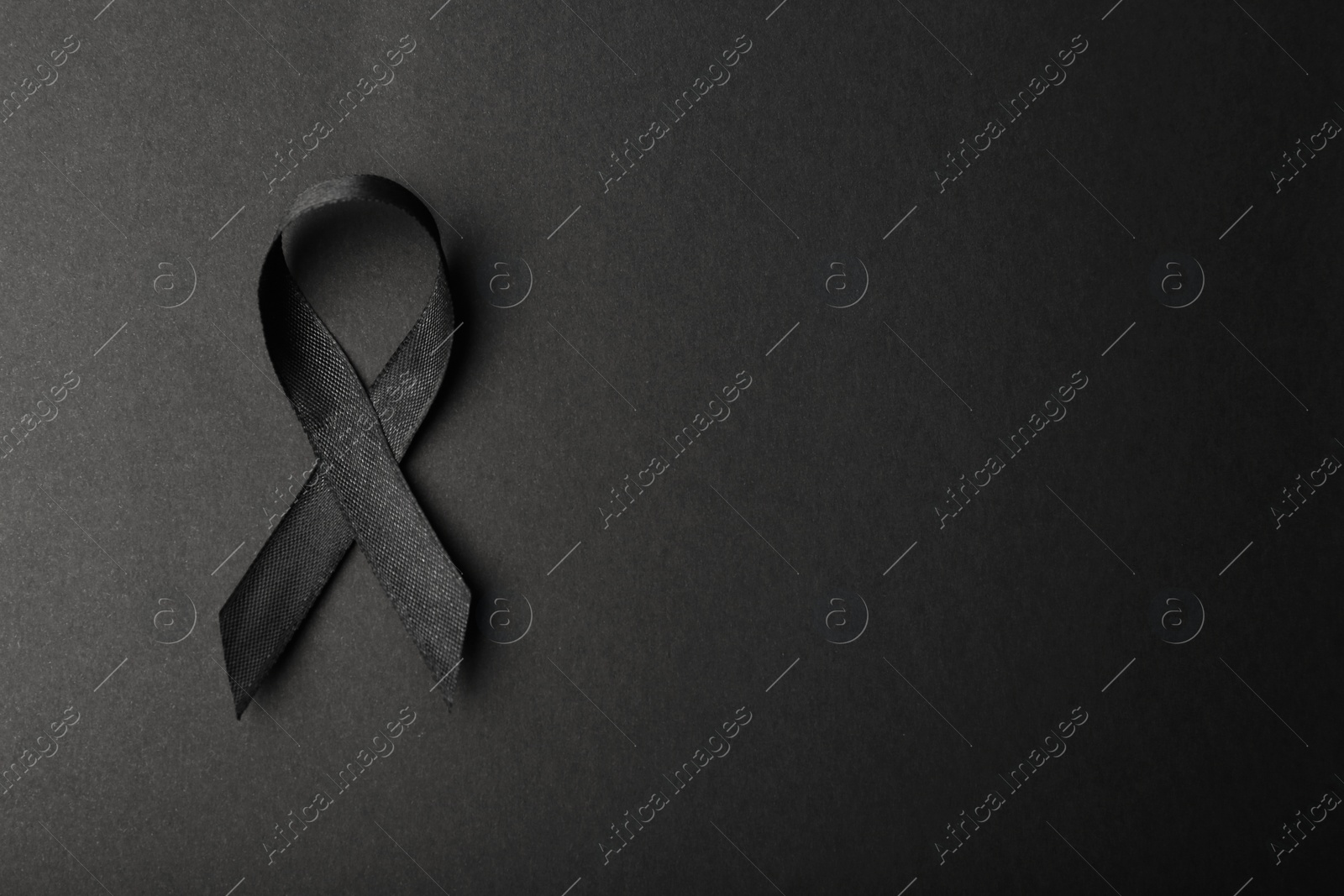 Photo of Black ribbon and space for text on dark background, top view. Funeral accessory