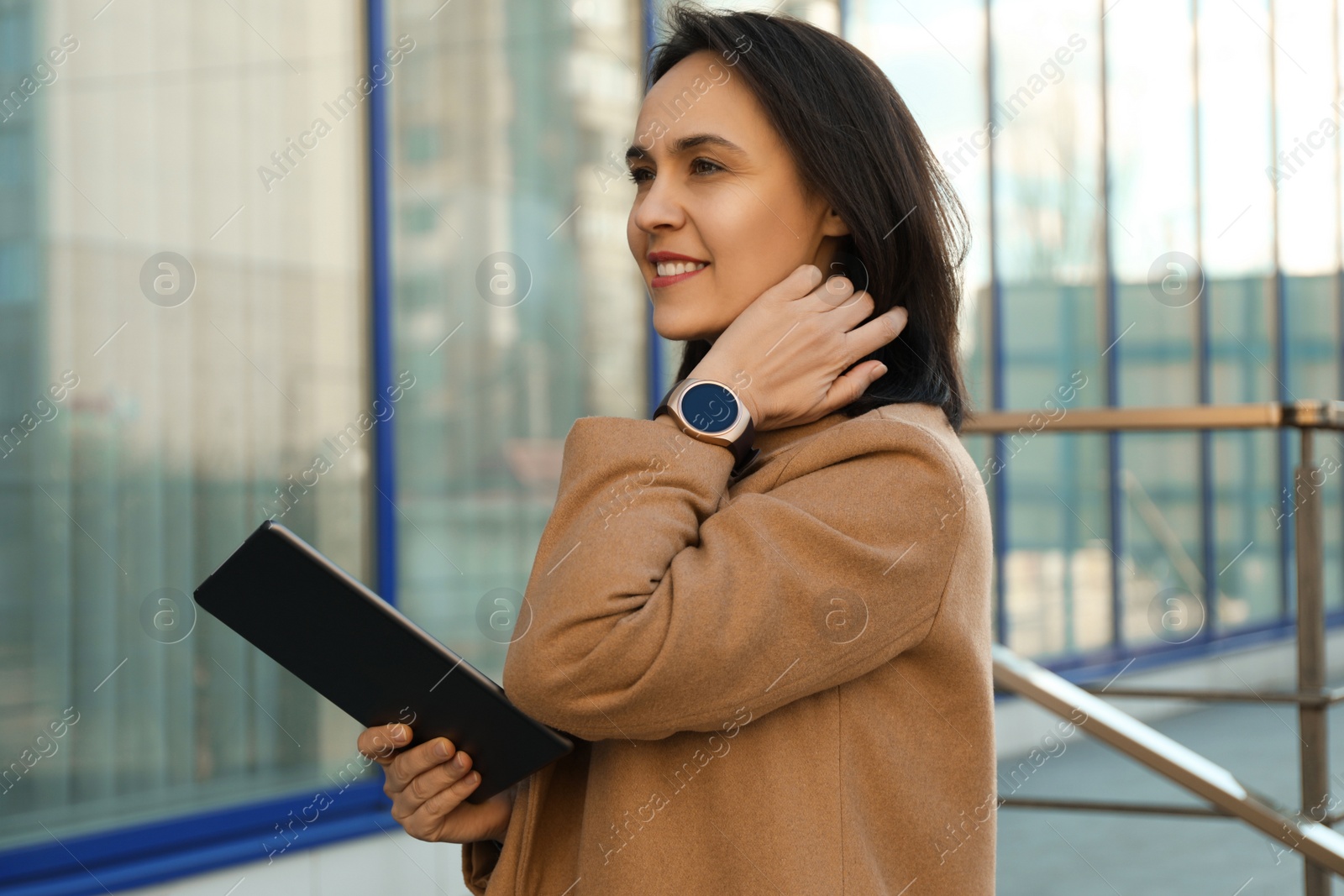 Photo of Mature woman with tablet and smart watch outdoors