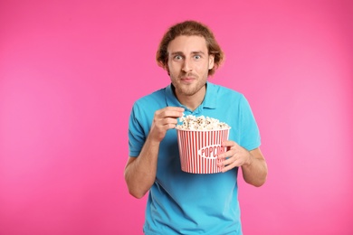 Man with popcorn during cinema show on color background