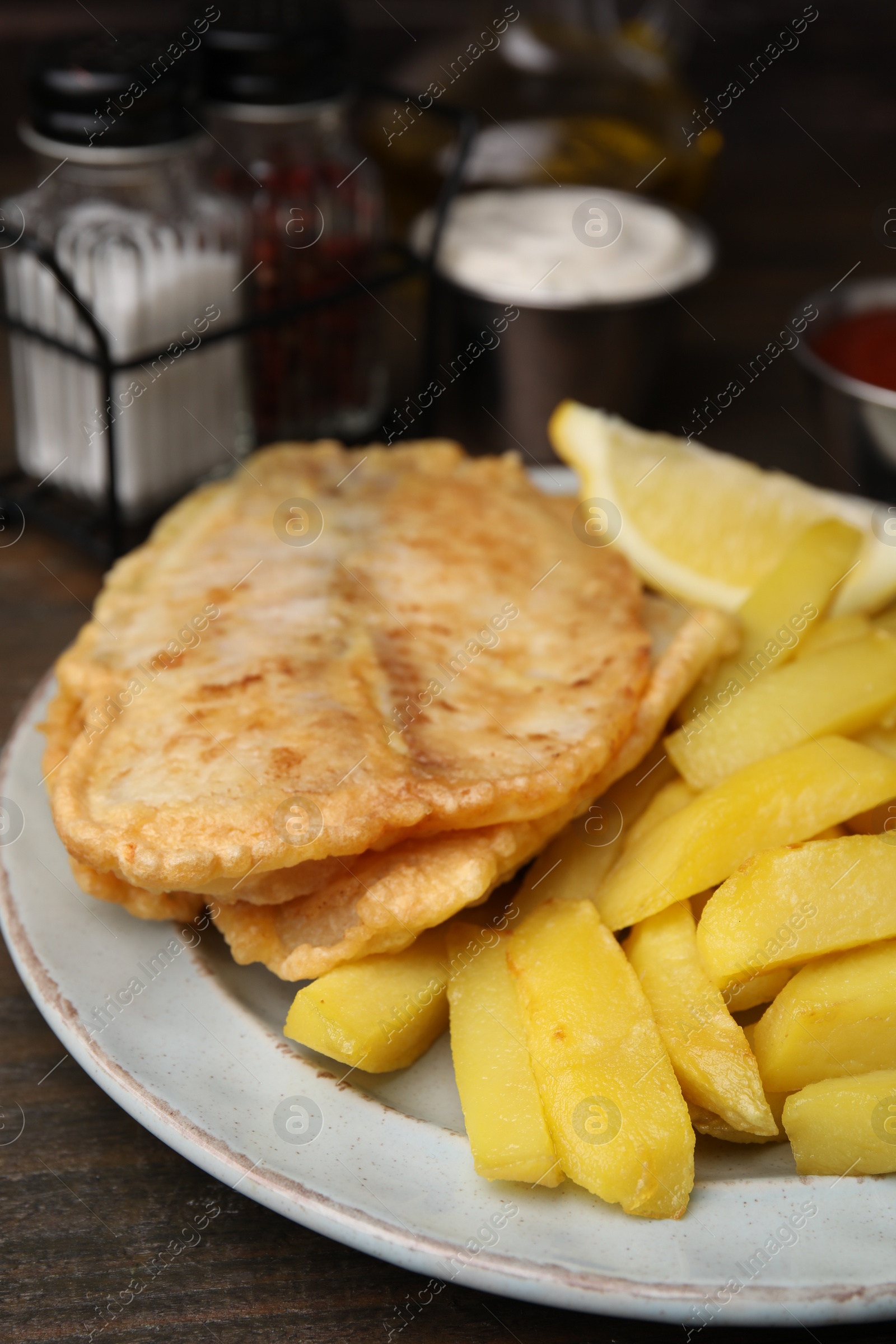 Photo of Delicious fish and chips on wooden table, closeup