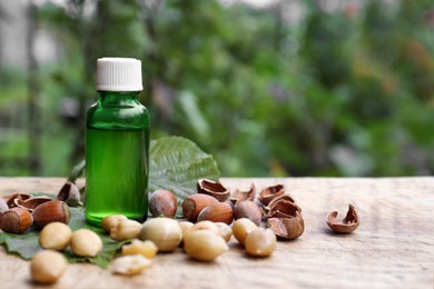 Photo of Bottle of hazelnut essential oil and nuts on wooden table. Space for text