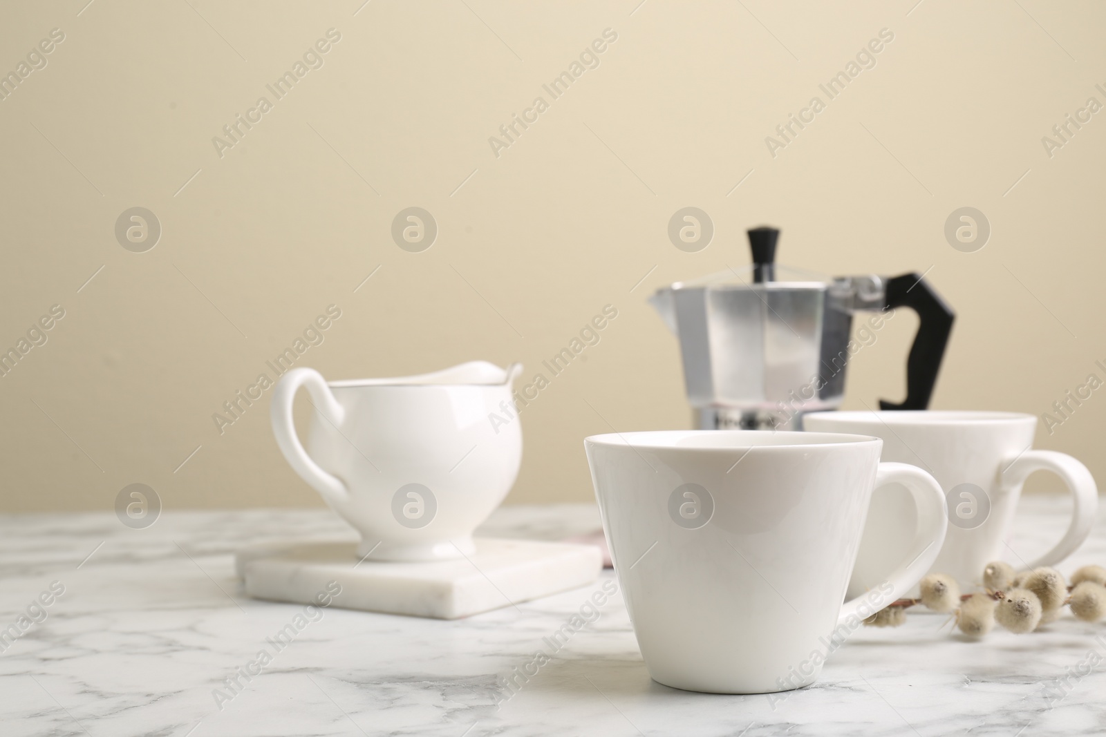 Photo of Cups, moka pot and jug on white marble table. Space for text