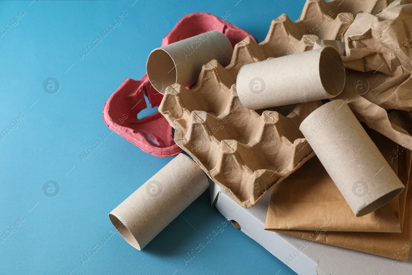 Photo of Different waste paper on light blue background, closeup. Space for text