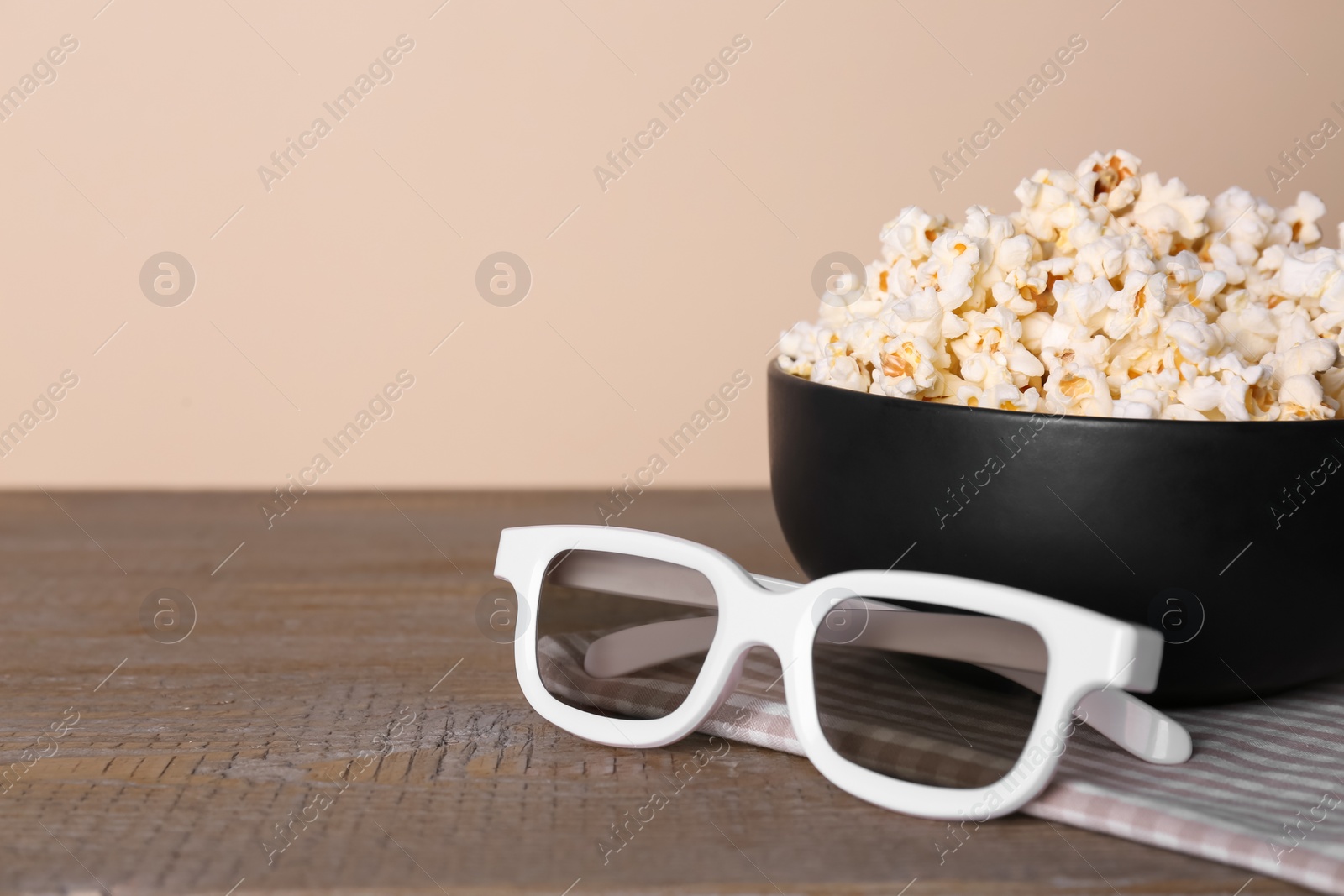Photo of Delicious popcorn and 3D glasses on wooden table. Space for text