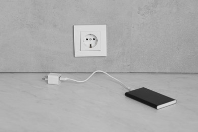 Photo of Electric socket and power bank on white table