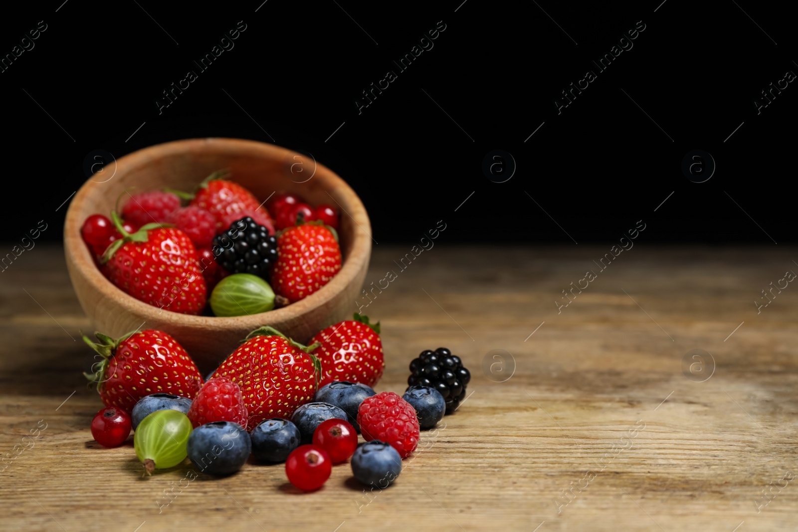 Photo of Mix of ripe berries on wooden table. Space for text