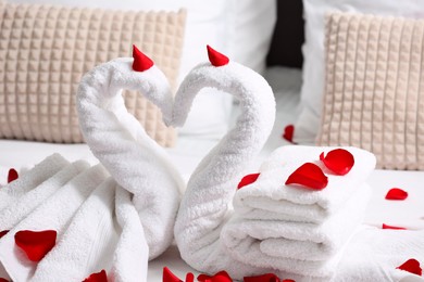 Photo of Honeymoon. Swans made with towels and beautiful rose petals on bed