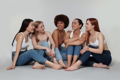 Group of beautiful young women sitting on light grey background