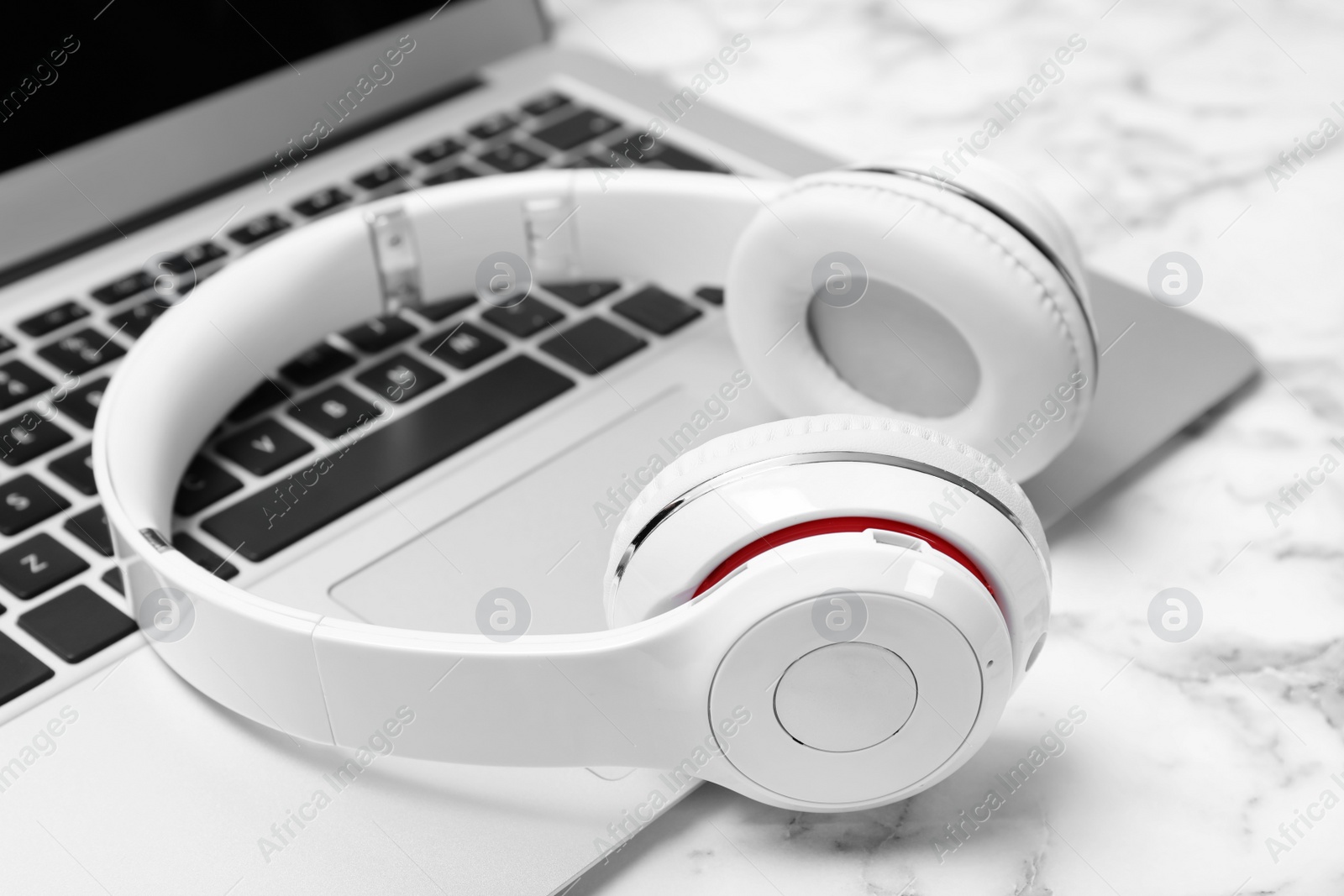 Photo of Modern headphones and laptop on table, closeup