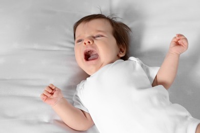 Photo of Cute little baby crying on soft bed