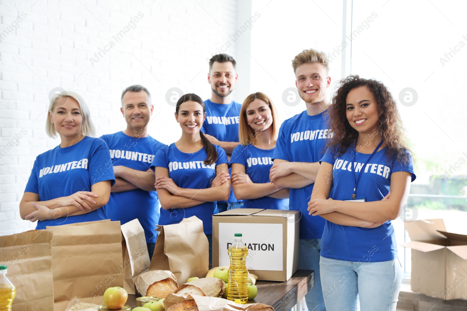 Photo of Team of volunteers near table with food donations indoors