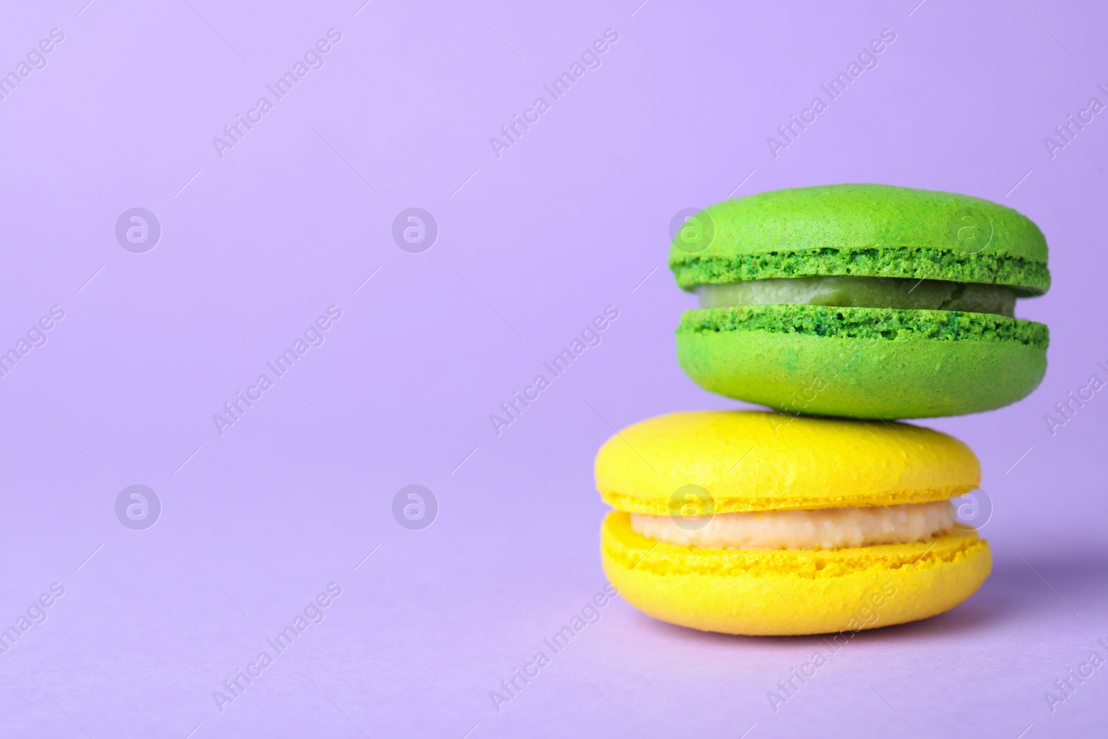 Photo of Delicious colorful macarons on violet background, closeup. Space for text