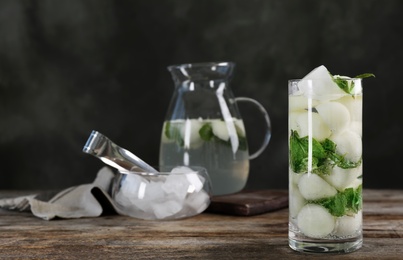 Glass with tasty melon ball drink on wooden table