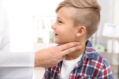 Doctor checking little boy's pulse with fingers in hospital