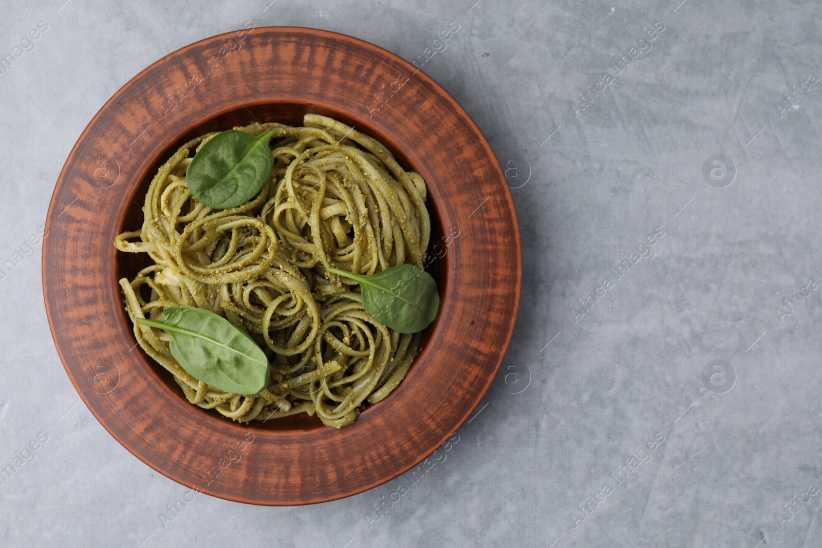 Photo of Tasty pasta with spinach on grey table, top view. Space for text