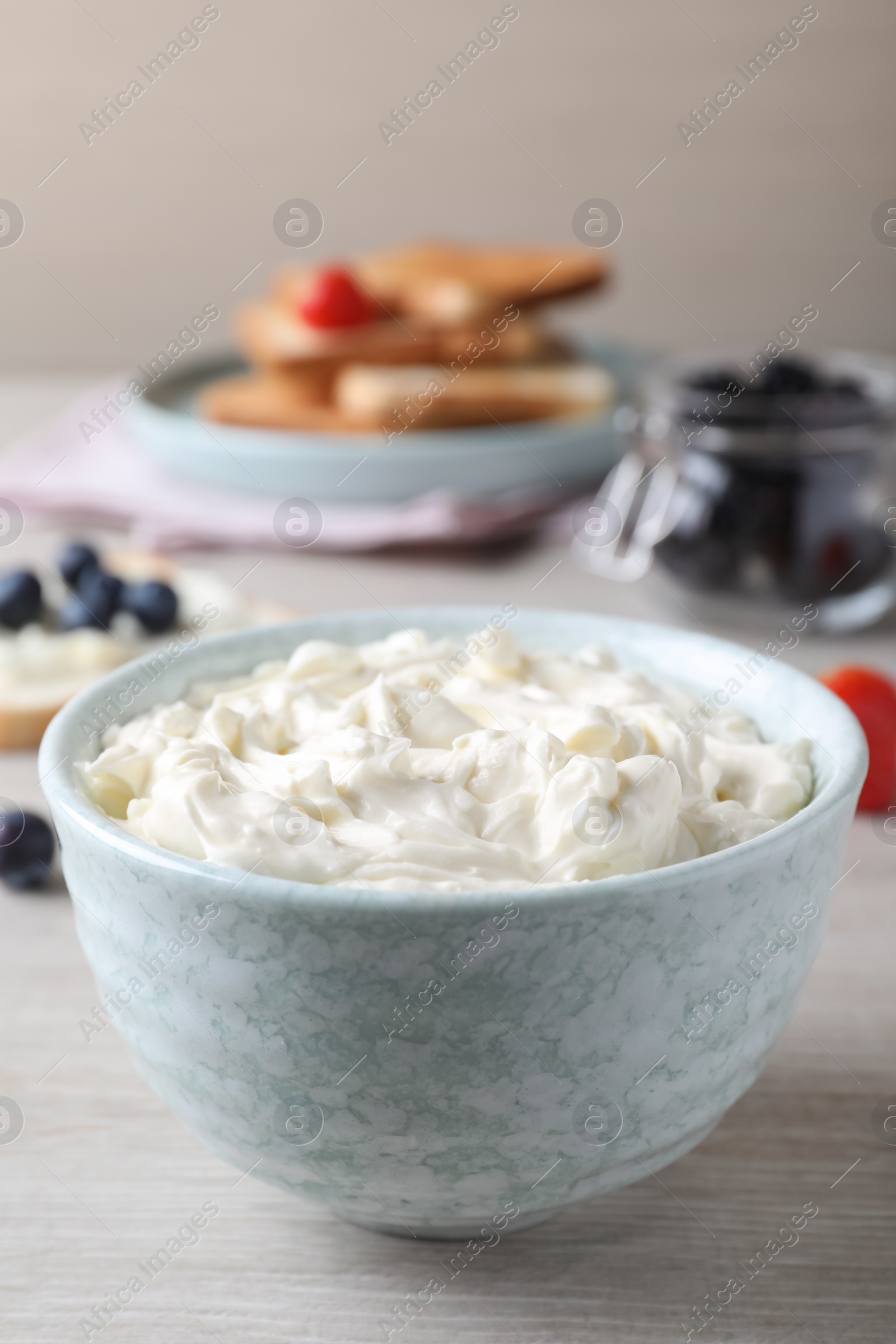 Photo of Tasty cream cheese and fresh berries on white wooden table