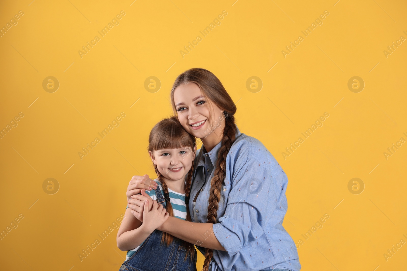 Photo of Happy woman and daughter in stylish clothes on color background