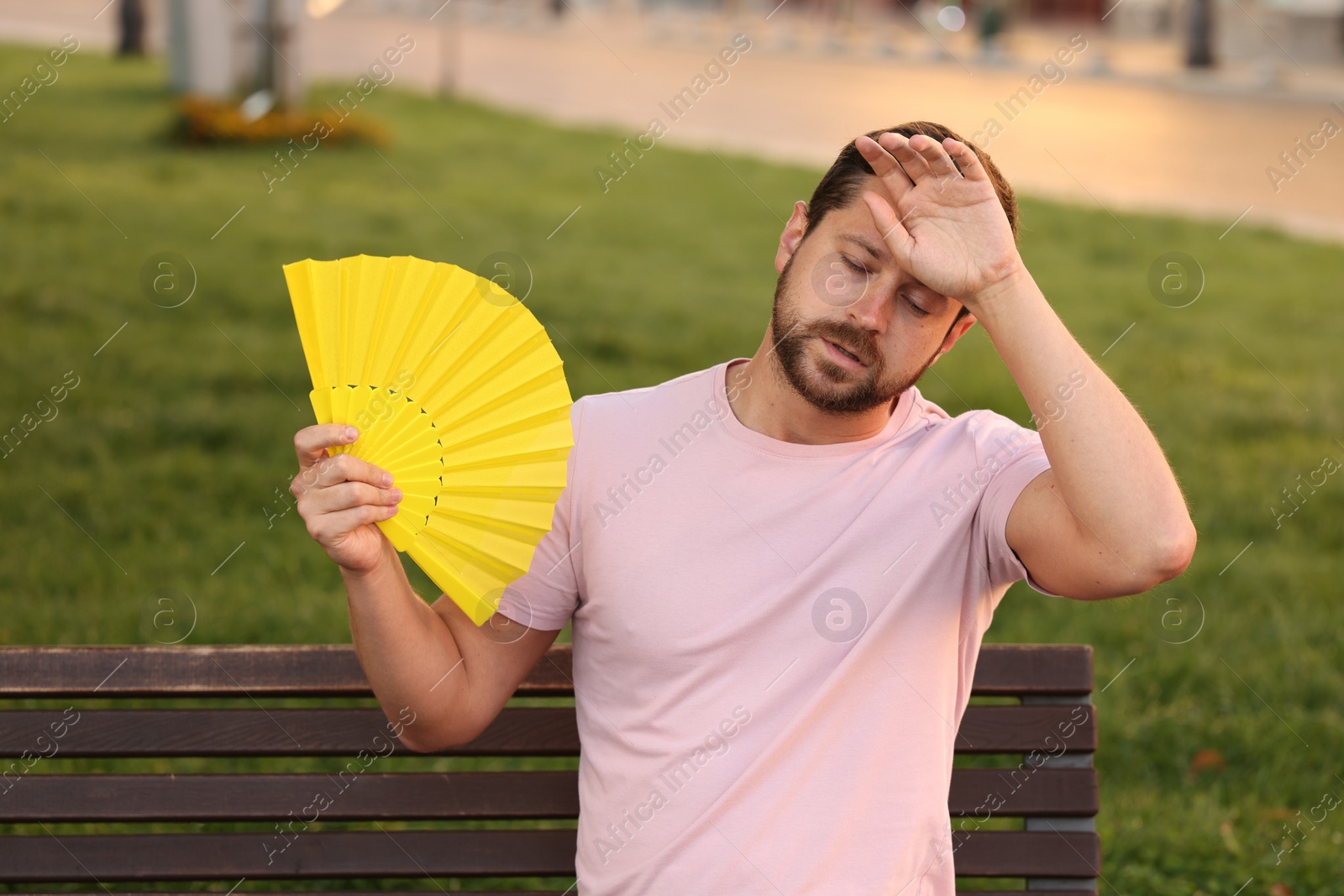 Photo of Man with hand fan suffering from heat outdoors