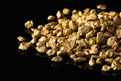 Photo of Pile of gold nuggets on black background, closeup