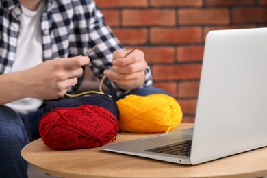 Man learning to knit with online course at home, closeup. Time for hobby