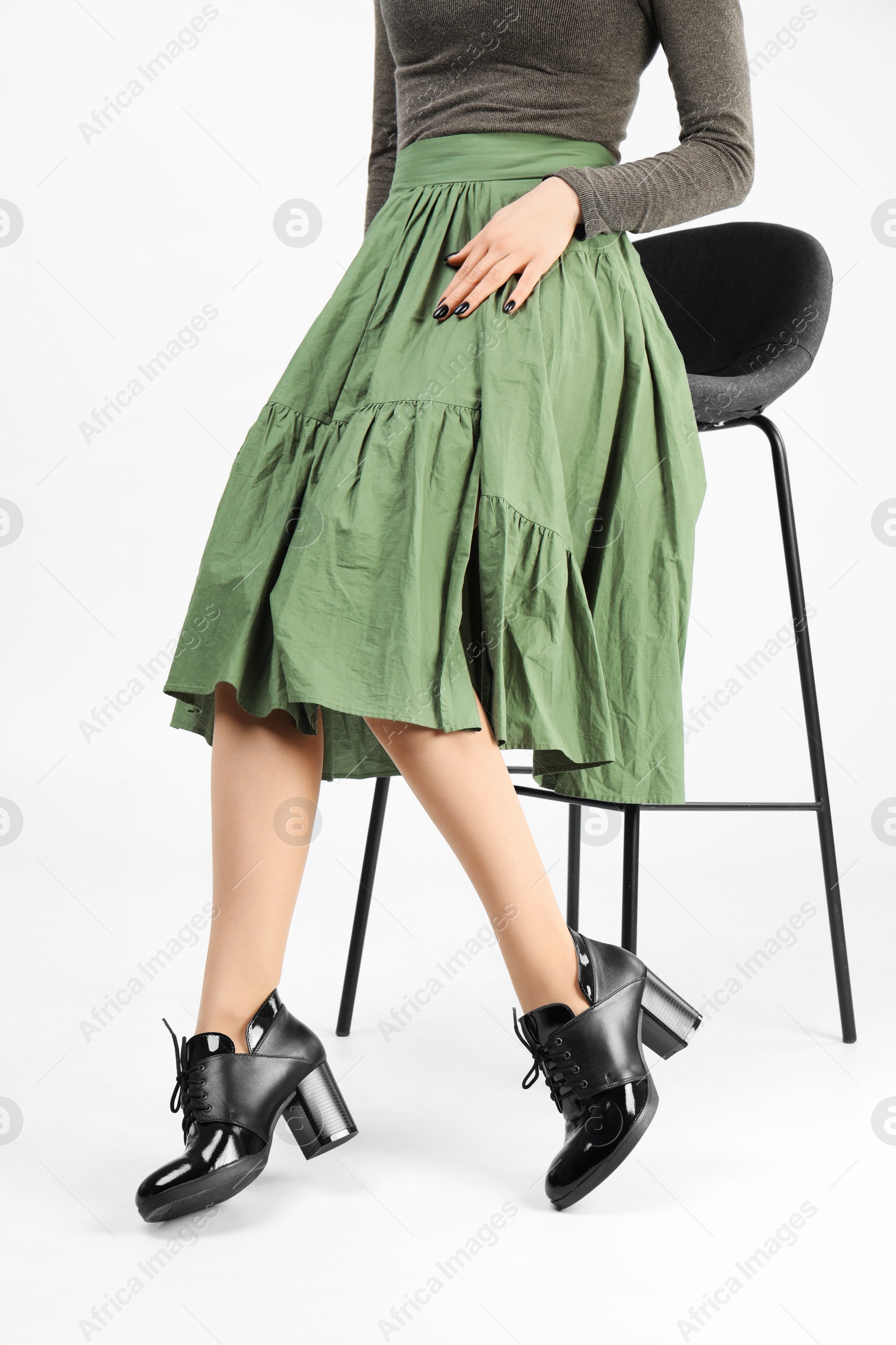 Photo of Woman in elegant shoes and bar stool on white background, closeup