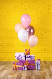 Many gift boxes and balloons near yellow brick wall