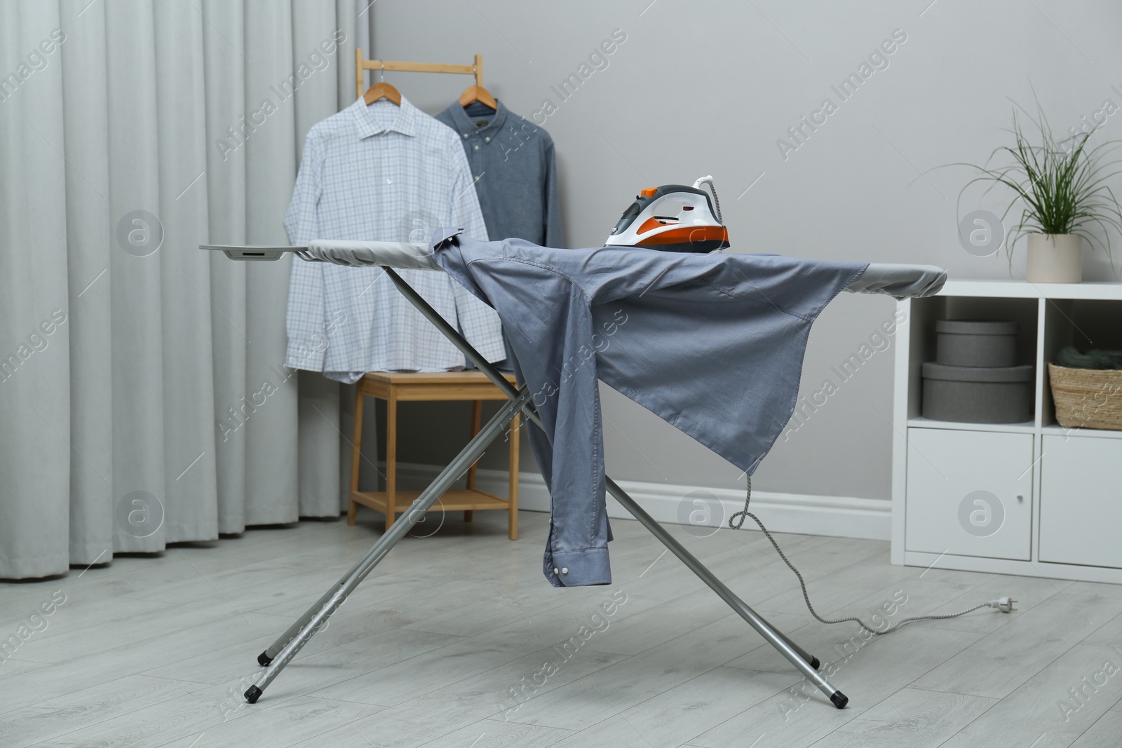 Photo of Modern iron and grey clean shirt on board indoors