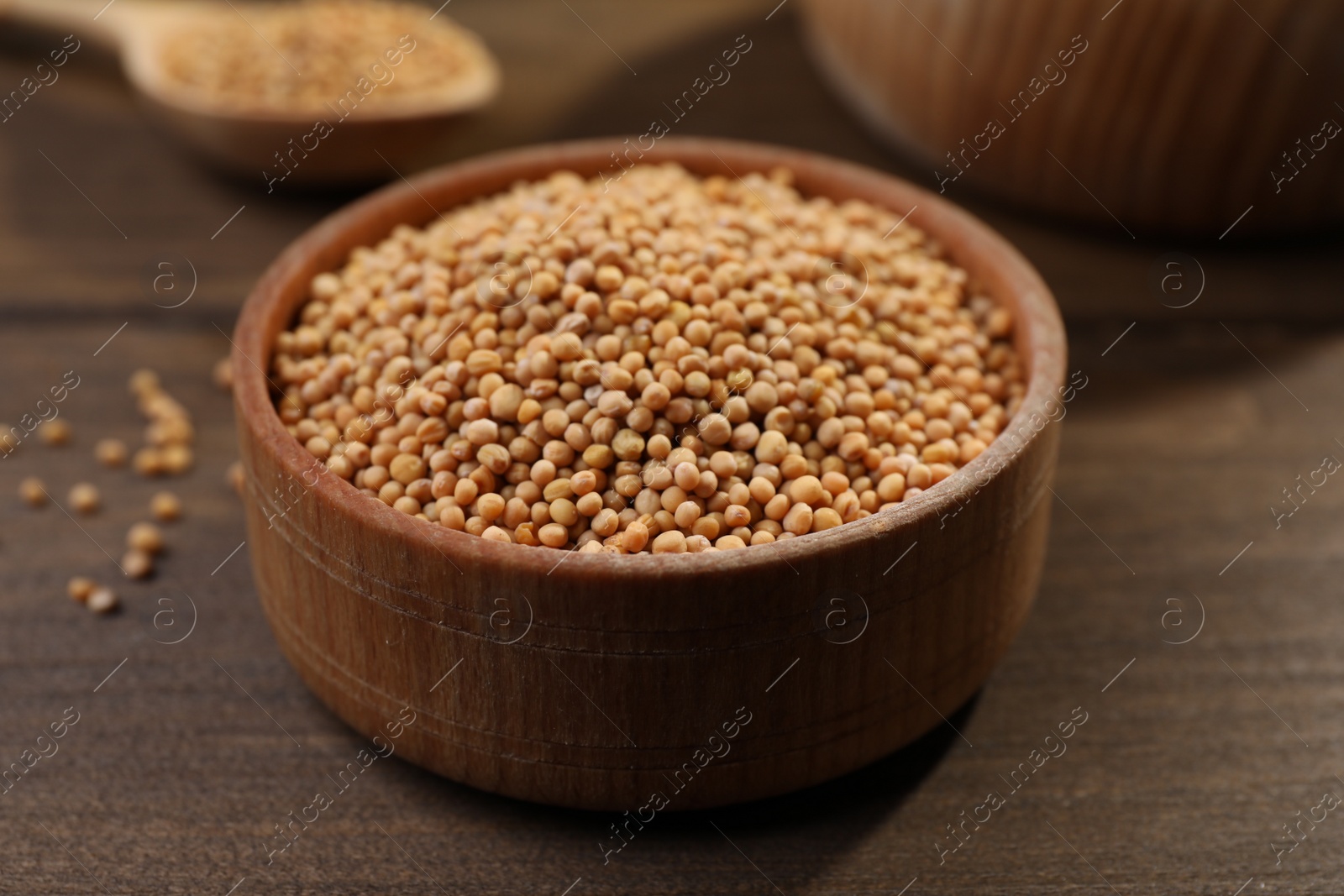 Photo of Mustard seeds in wooden bowl on table, closeup