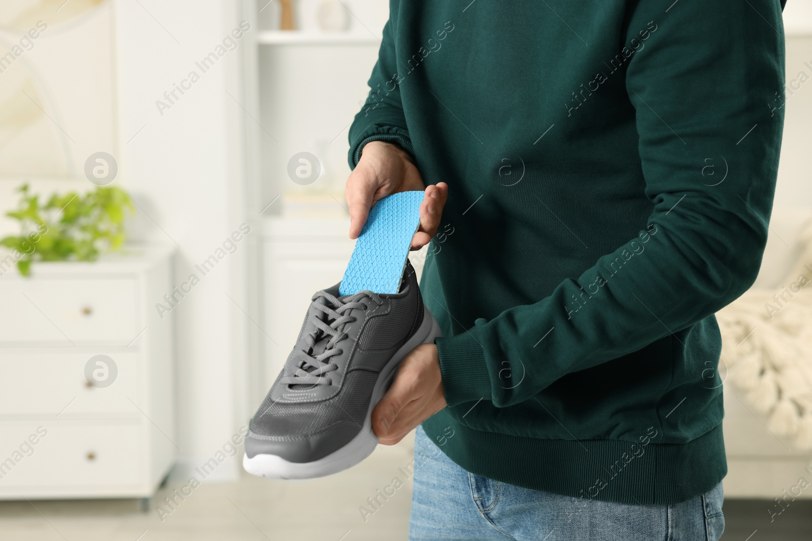 Photo of Man putting orthopedic insole into shoe indoors, closeup. Space for text