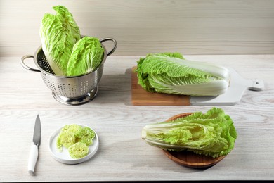 Photo of Whole and cut fresh ripe Chinese cabbages on white wooden table