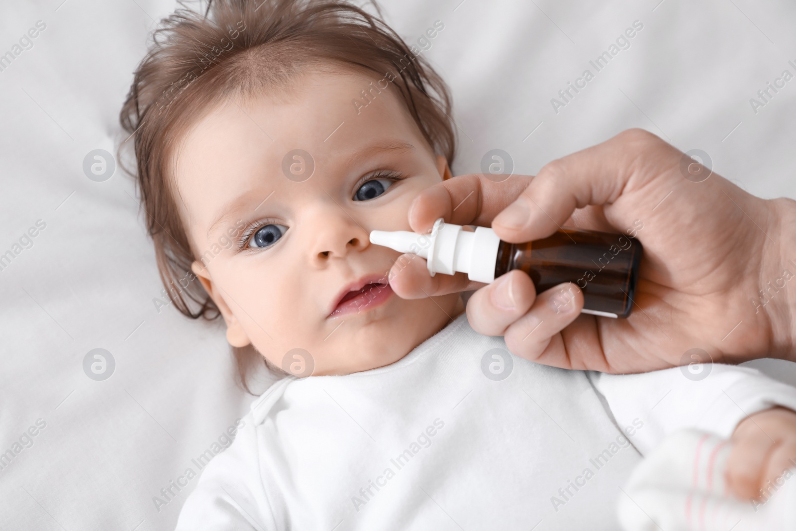 Photo of Father taking care of little baby suffering from runny nose in bed, top view