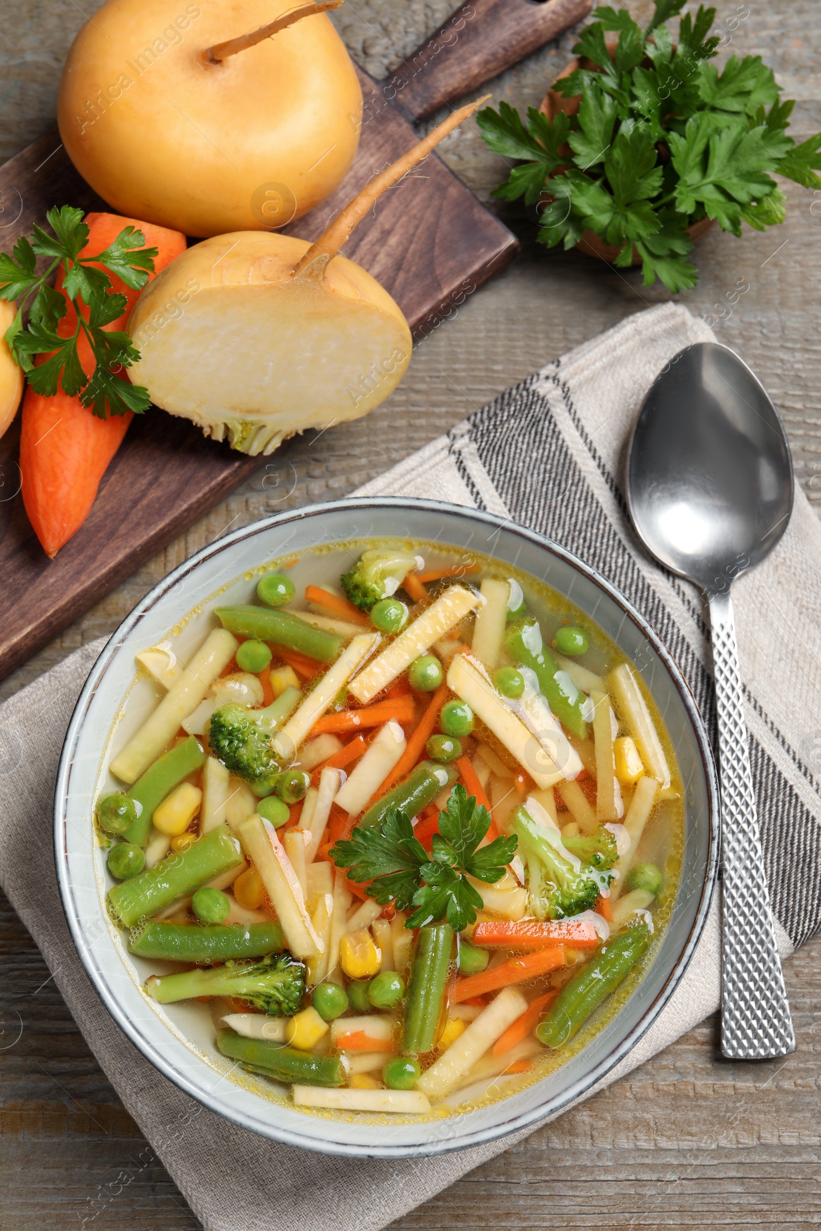 Photo of Bowl of delicious turnip soup served on wooden table, flat lay