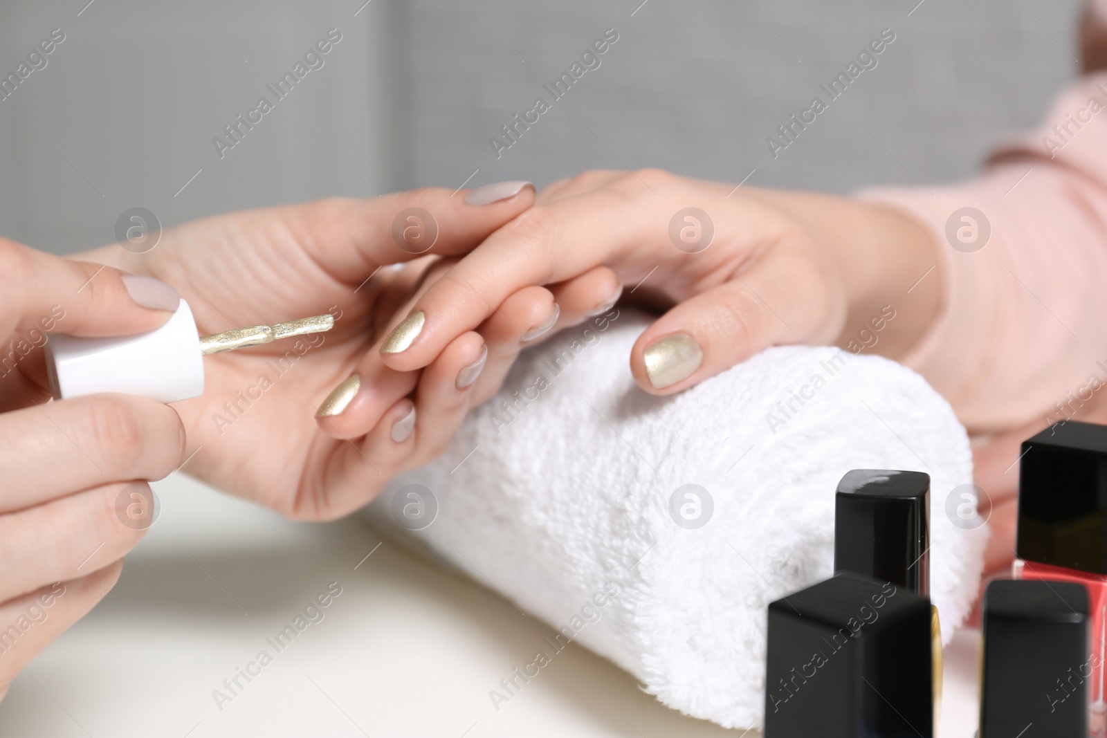 Photo of Manicurist painting client's nails with polish in salon, closeup