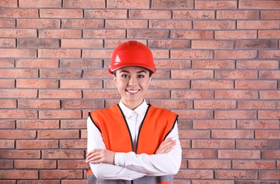 Female industrial engineer in uniform on brick wall background. Safety equipment