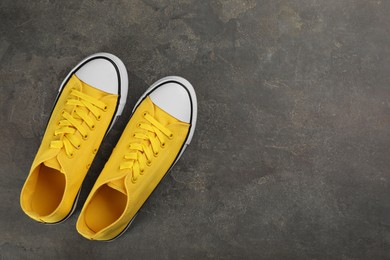 Photo of Pair of yellow sneakers on grey stone table, flat lay. Space for text