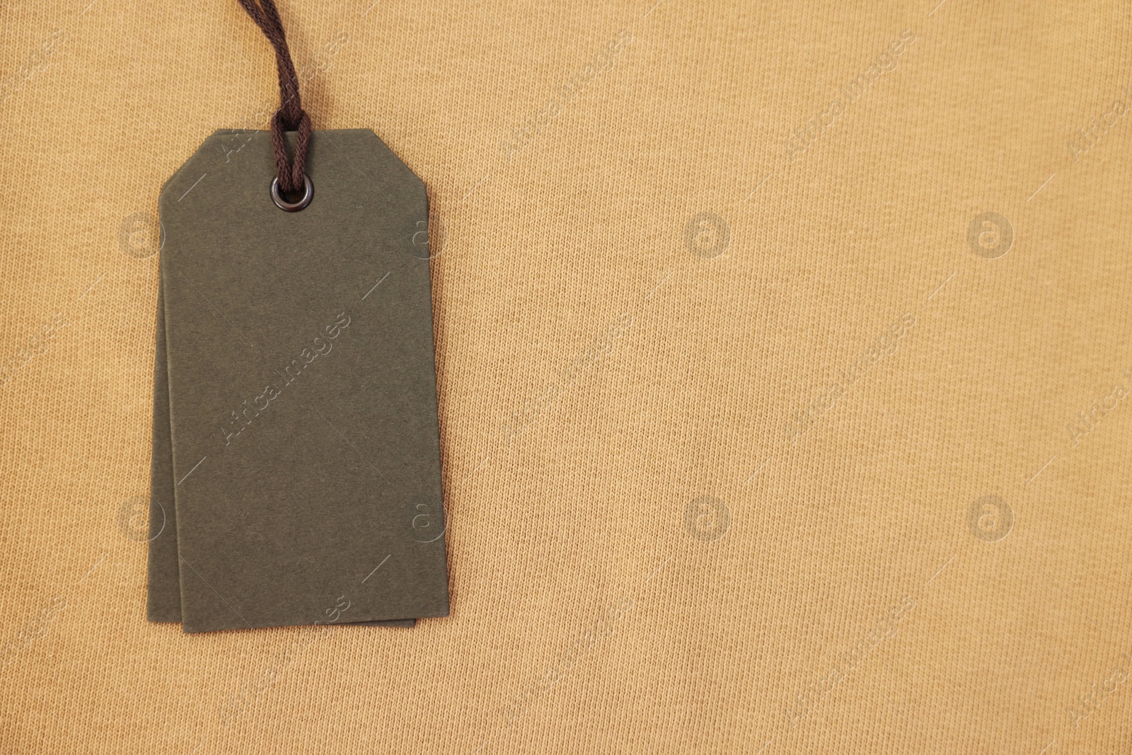 Photo of Cardboard tags on beige garment, top view. Space for text