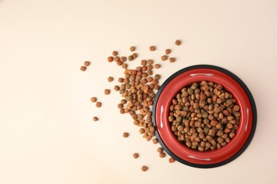Photo of Dry dog food and feeding bowl on beige background, flat lay. Space for text