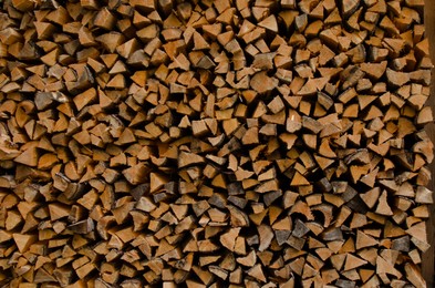 Photo of Stacked firewood as background. Heating house in winter, closeup