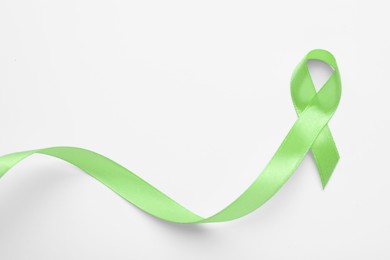 Photo of World Mental Health Day. Green ribbon on white background, top view with space for text