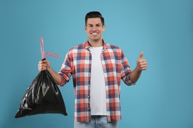 Photo of Man holding full garbage bag on light blue background