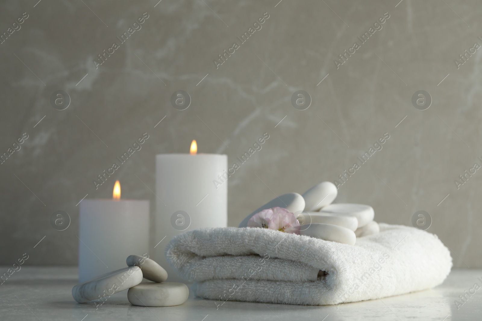 Photo of Spa stones, towel and burning candles on white table