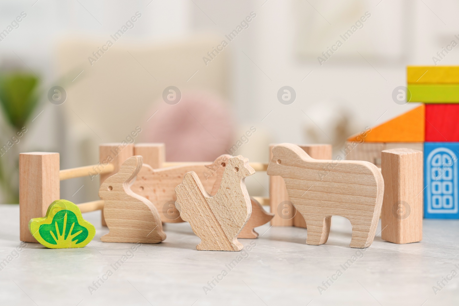 Photo of Wooden animals and fence on light grey table indoors, closeup. Children's toys