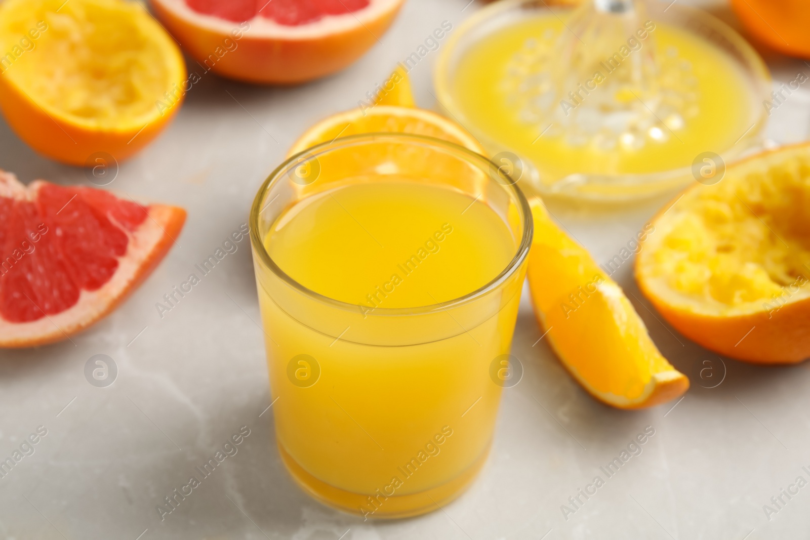 Photo of Freshly made orange juice, fruits and squeezer on table, closeup