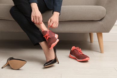 Photo of Woman changing shoes on sofa in office, closeup