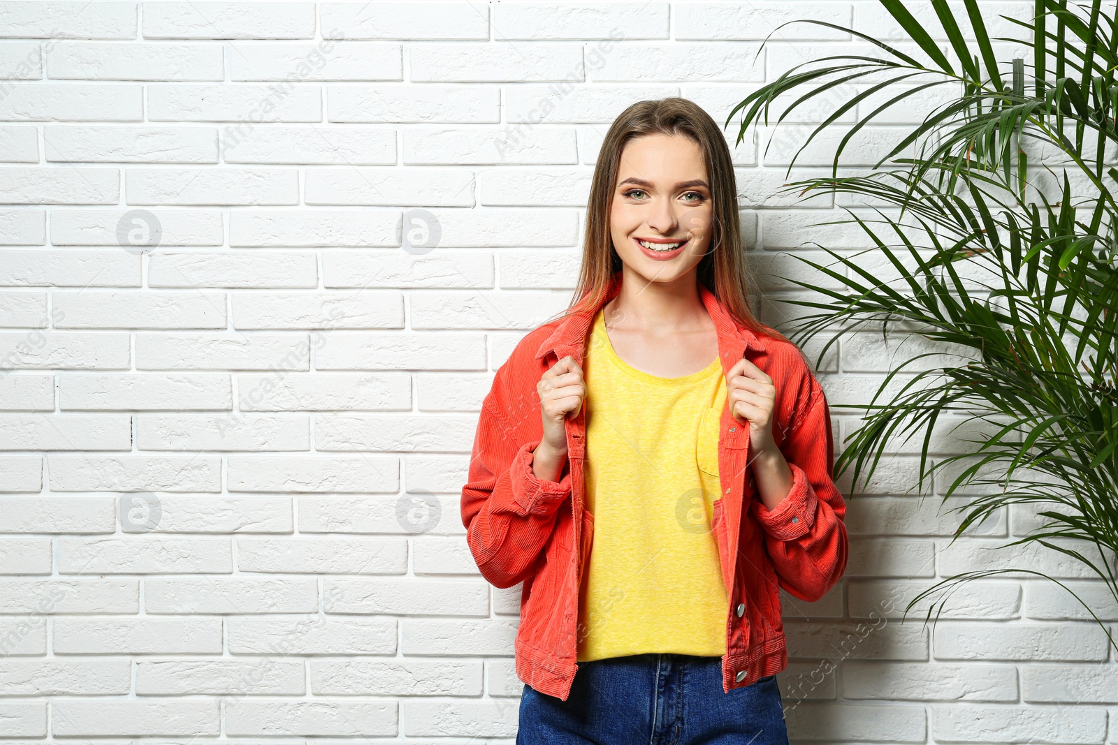 Photo of Young woman wearing blank t-shirt near white brick wall. Mockup for design