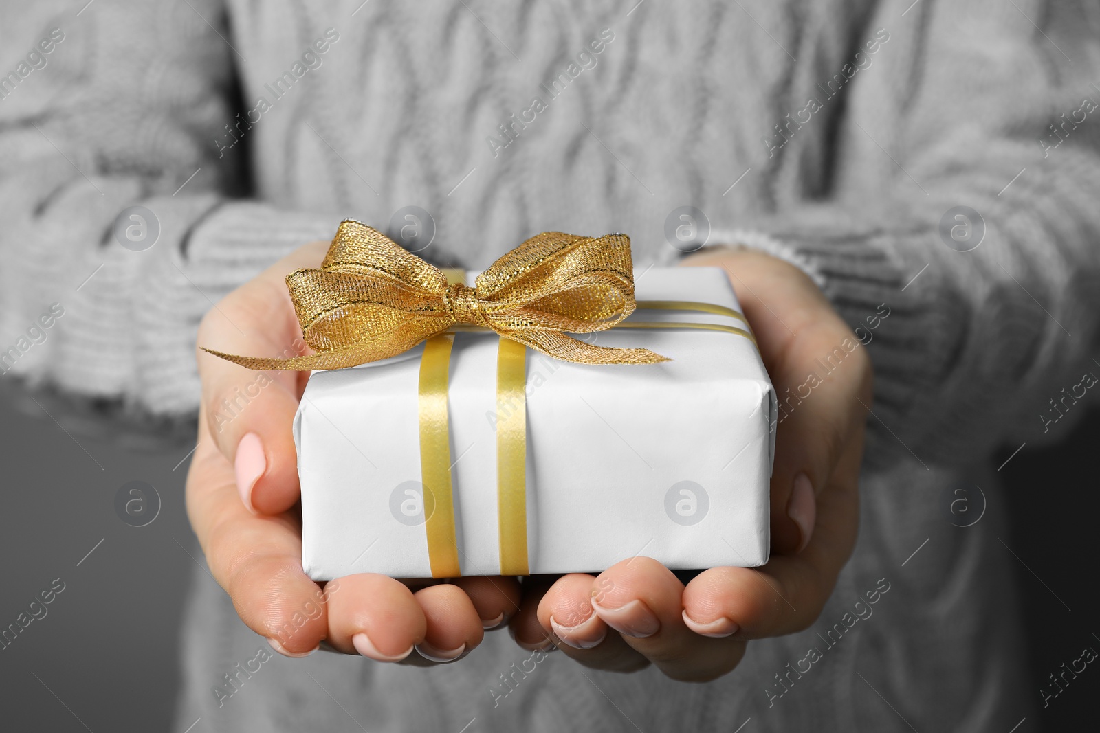 Photo of Christmas present. Woman holding gift box against grey background, closeup