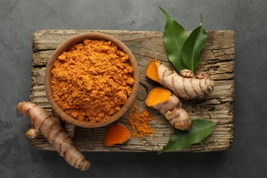 Photo of Aromatic turmeric powder and raw roots on grey table, top view